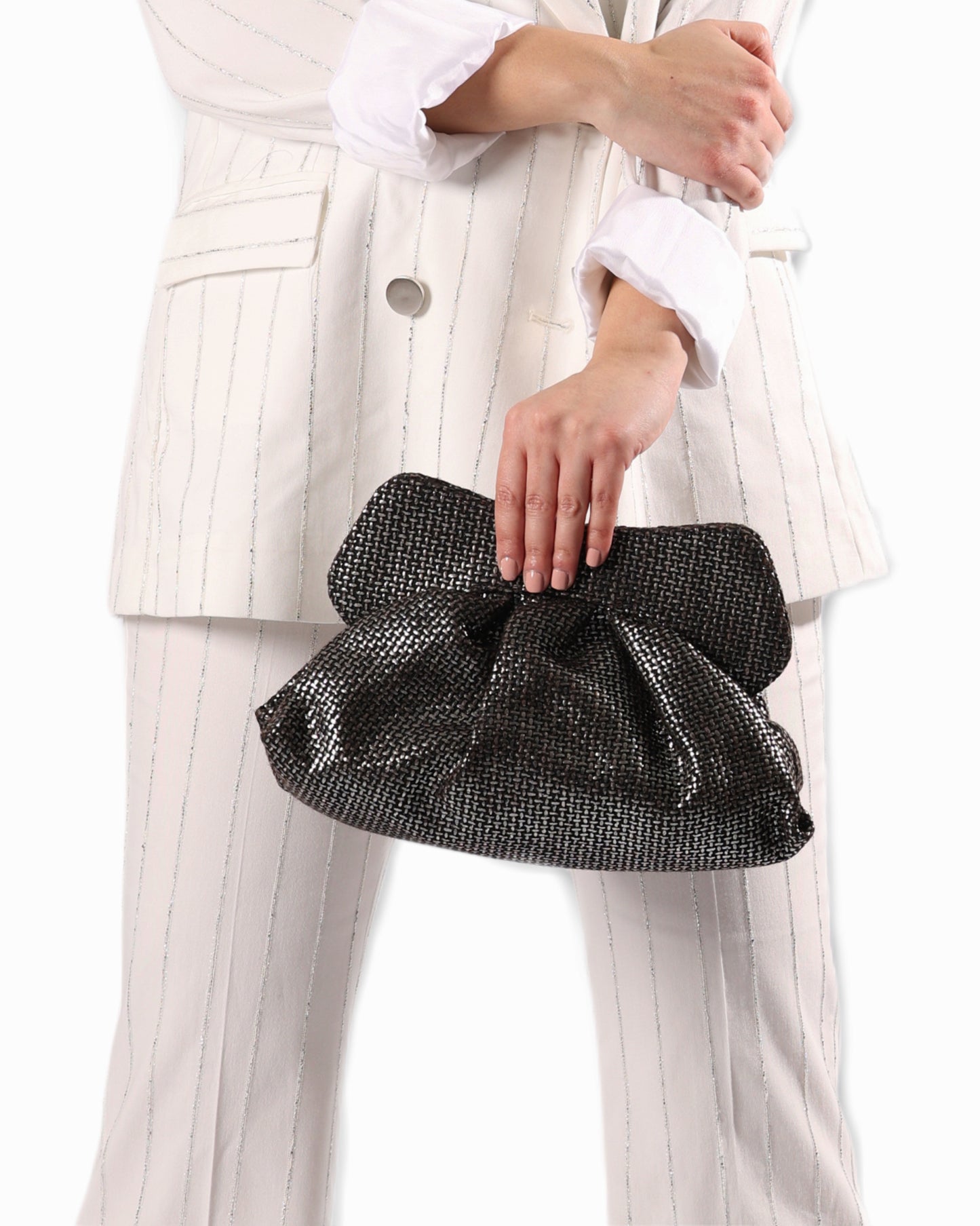 Person holding a black silver clutch bag with a white outfit