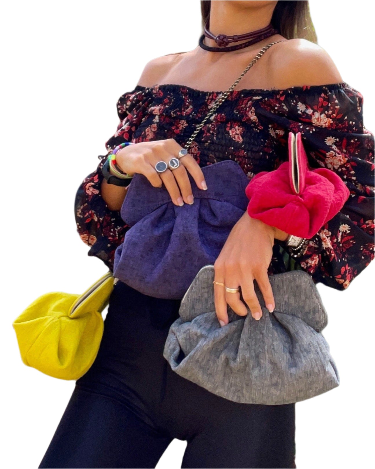 Woman holding colorful handbags with a floral off-shoulder top on a white background