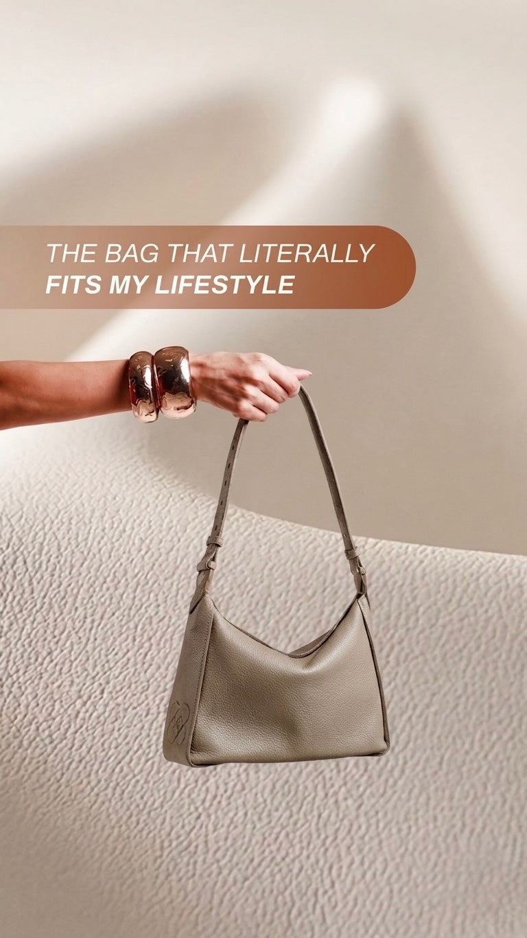 woman showing the lea shoulder bag how soft slouchy and practical it is . bag in genuine greige leather